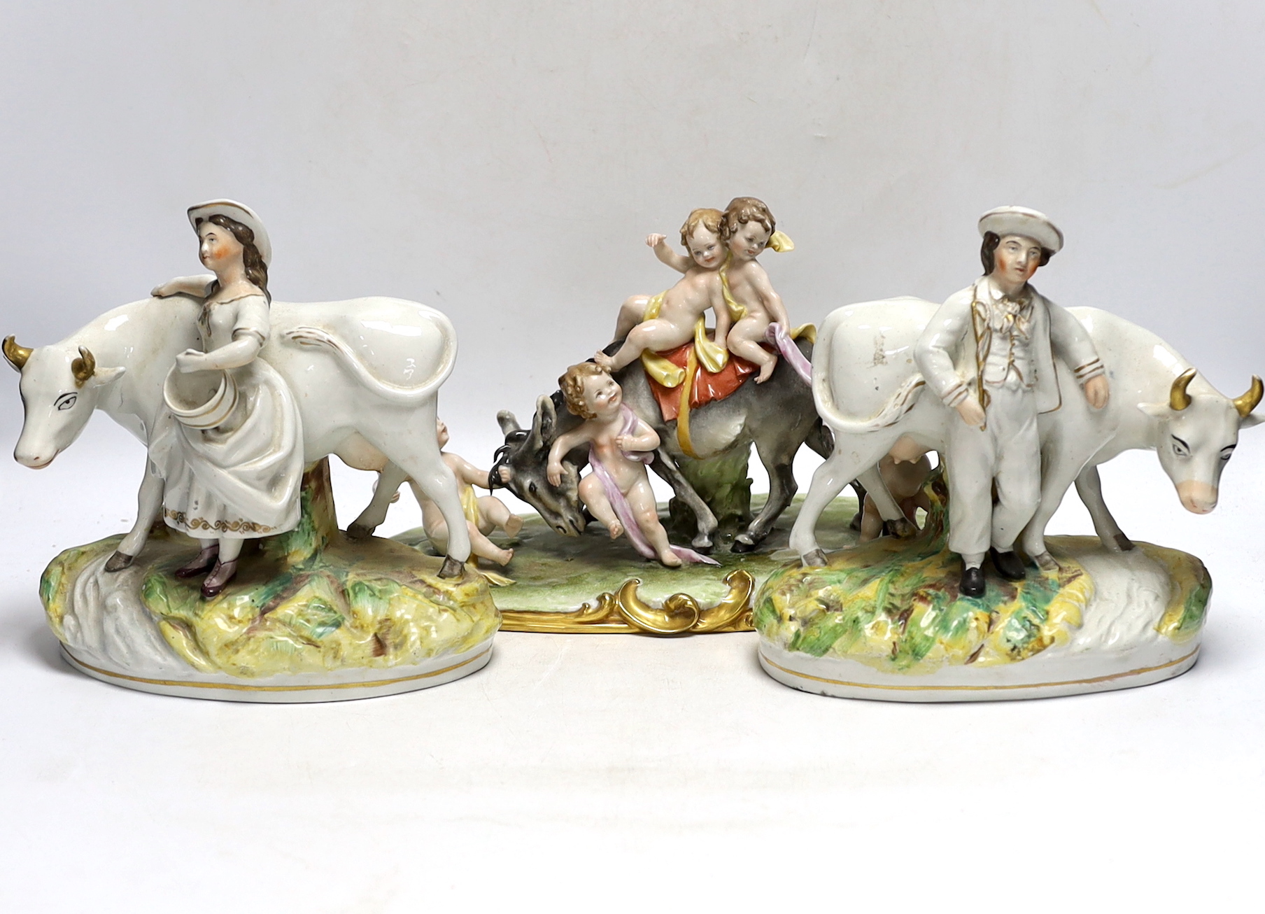 A pair of 19th century Staffordshire cow groups and an Italian donkey and cherub group, tallest 20.5cm